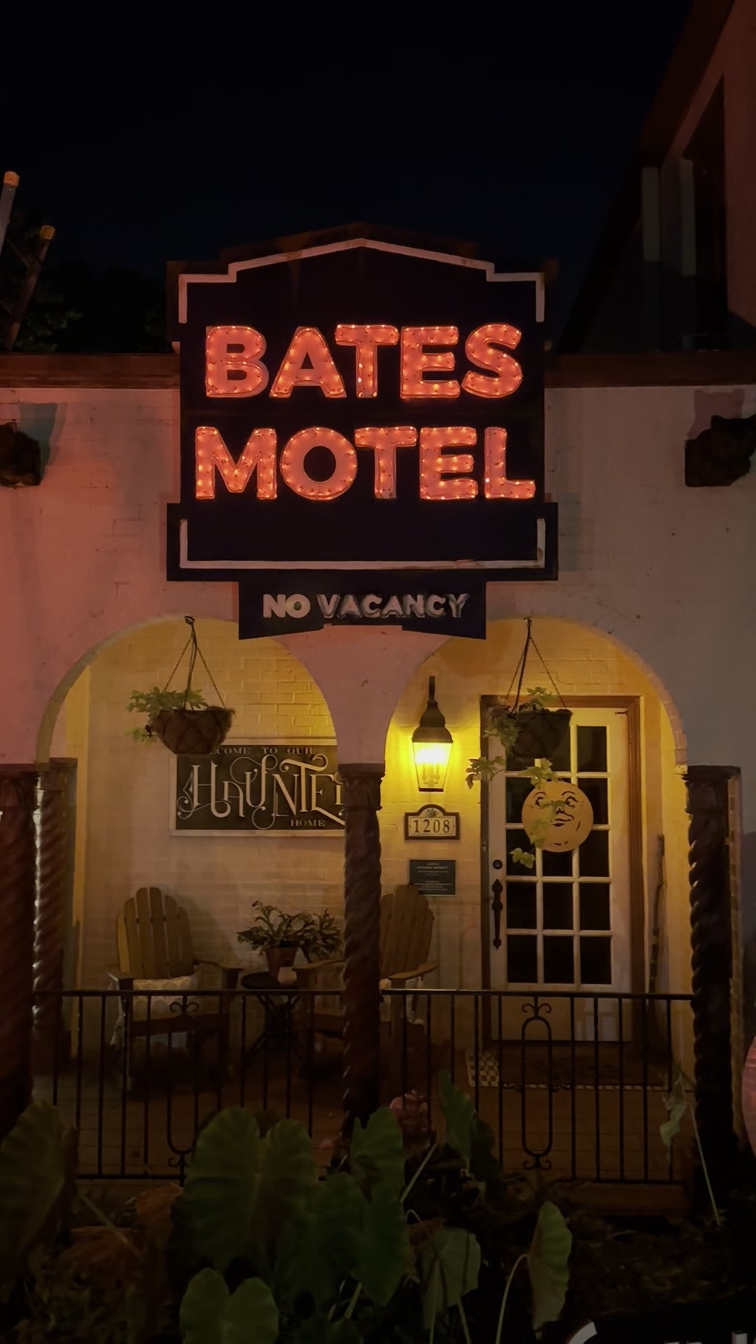 DIY Bates Motel sign lit up in orange faux neon on a house for Halloween